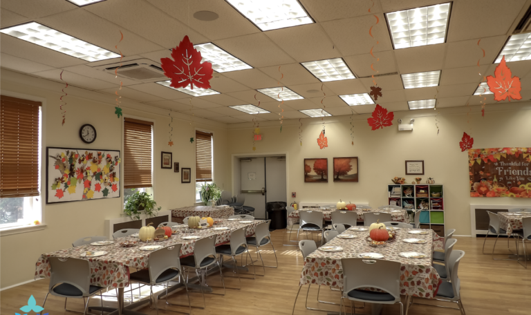 A drink station featuring three glass dispensers filled with water, apple cider, and sweet tea, labeled with charming leaf-shaped signs on a fall-themed table at the Thanksgiving 2024 'Friendsgiving' Event by Home Not Alone Caregiver Services for individuals with intellectual disability (IDD) within residential group homes and accessible family group homes in Allegheny County, Pittsburgh, Pennsylvania.