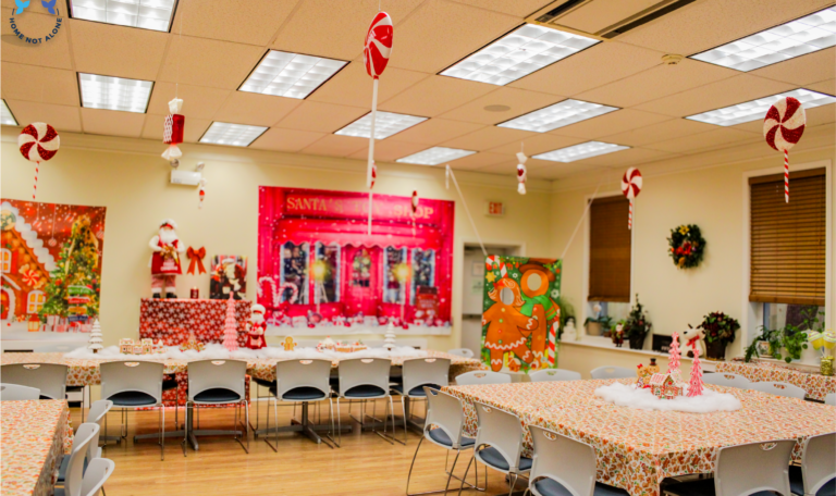 A beautifully decorated holiday space with candy cane-themed hanging ornaments, festive table settings, and a Santa’s Toy Shop backdrop. Home Not Alone Christmas Event 2024/ Holiday Event in Holiday Season by Home Not Alone Caregiver Services for individuals with intellectual disability (IDD) within residential group homes and accessible family group homes in Allegheny County, Pittsburgh, Pennsylvania.