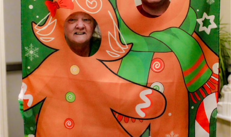 a client and her family member enjoying cocoa and holiday treats at a festive table decorated with gingerbread-themed ornaments. Home Not Alone Christmas Event 2024/ Holiday Event in Holiday Season by Home Not Alone Caregiver Services for individuals with intellectual disability (IDD) within residential group homes and accessible family group homes in Allegheny County, Pittsburgh, Pennsylvania.