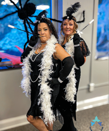 Two women dressed in stylish Halloween outfits posing together during the Home Not Alone celebration, adding elegance to the spooky fun. Provided by Home Not Alone Caregiver Services for individuals with intellectual disability and Autism (ID/A) within Community for Disabled Adults and accessible family group homes in Allegheny County, Pittsburgh, Pennsylvania.