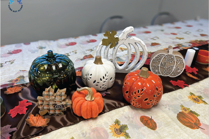 A fall-themed table arrangement featuring pumpkins, leaves, and seasonal centerpieces displayed during the Home Not Alone Friendsgiving event. Provided by Home Not Alone Caregiver Services for individuals with intellectual disability and Autism (ID/A) within Community for Disabled Adults and accessible family group homes in Allegheny County, Pittsburgh, Pennsylvania.