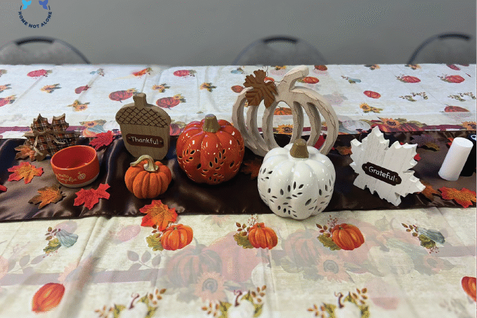 Decorative Thanksgiving pumpkins and “Thankful” and “Grateful” signs placed on a fall table runner during the Home Not Alone Friendsgiving celebration. Provided by Home Not Alone Caregiver Services for individuals with intellectual disability and Autism (ID/A) within Community for Disabled Adults and accessible family group homes in Allegheny County, Pittsburgh, Pennsylvania.